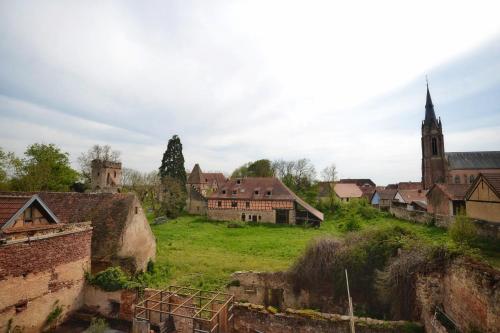 an old village with a church in the background at Maison 1686 in Niedernai