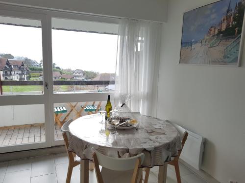 une salle à manger avec une table et des chaises et une fenêtre dans l'établissement 2/3 Pièces - Balcon Vue Mer - Parking, à Trouville-sur-Mer