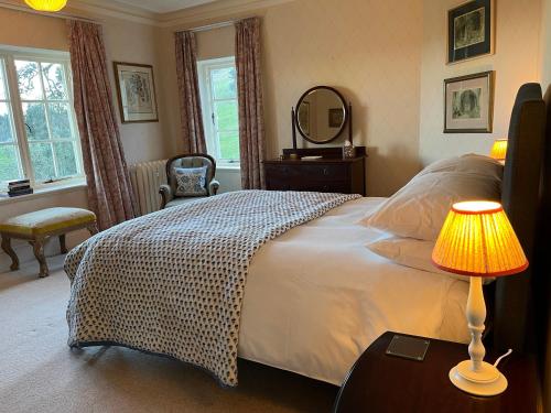 a bedroom with a bed with a lamp and a mirror at Yearle House in Wooler