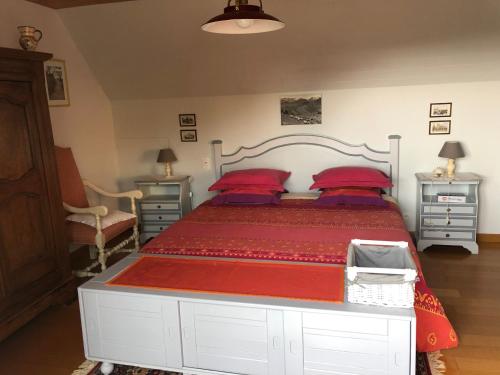 a bedroom with a large bed with red sheets and red pillows at Liorzh an ty in Kerfany-les-Pins