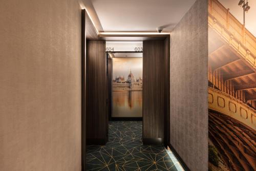 a corridor of a hotel room with a hallway with a painting at Eurostars Ambassador in Budapest