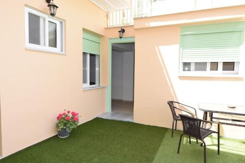 patio ze stołem i krzesłami na zielonym dywanie w obiekcie Ηermes Apartment - 3 w Nauplionie