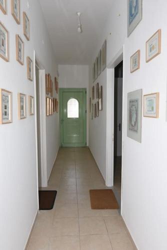 a hallway with a green door and pictures on the walls at Ηermes Apartment - 3 in Nafplio