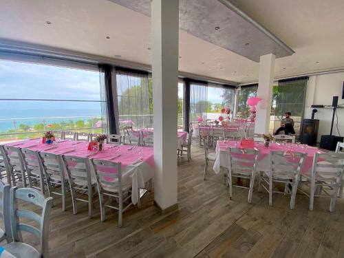 een kamer met tafels en stoelen met roze tafelkleden bij Frontemare Village - Hotel, Ristorante & SPA - in Rodi Garganico
