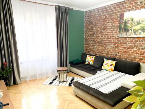 a living room with a couch and a brick wall at Asha Central Apartment in Timişoara