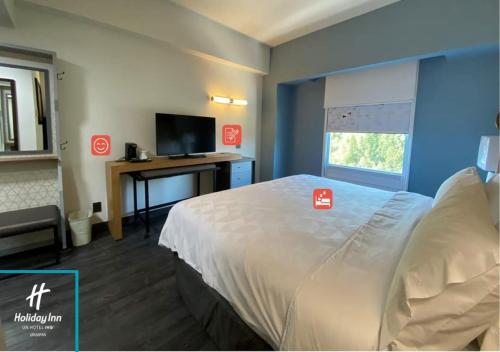 a hotel room with a bed and a desk with a television at Holiday Inn Uruapan by IHG in Uruapan del Progreso