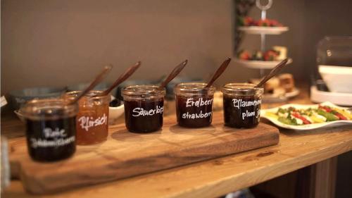 a table with four jars of honey and a plate of food at Pension & Seminarhaus "Haus am Fluss" in Laurenburg