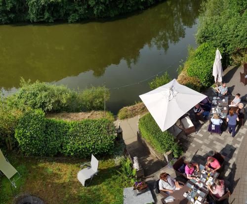 a group of people sitting at tables next to a river at Pension & Seminarhaus "Haus am Fluss" in Laurenburg