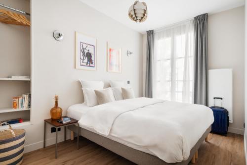 une chambre avec un grand lit blanc et une fenêtre dans l'établissement Edgar Suites Champs Elysées - Boétie, à Paris