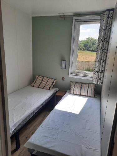 une petite chambre avec deux lits et une fenêtre dans l'établissement Mobil Home tout confort, à Saint-Hilaire-de-Riez