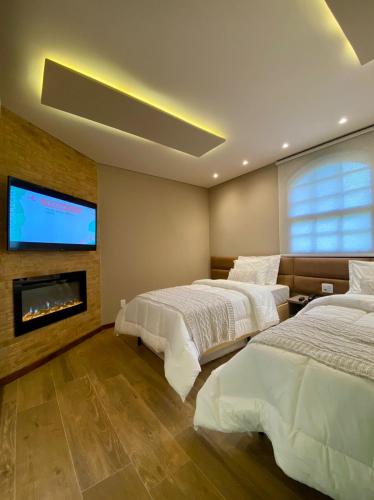 a bedroom with two beds and a flat screen tv at Hotel Fazenda Vilarejo All Inclusive in Conservatória