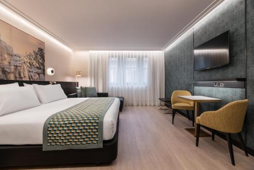 a hotel room with a bed and a table and chairs at Eurostars Ambassador in Budapest