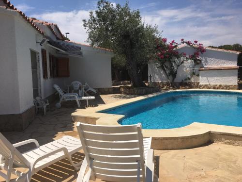 a swimming pool with two chairs next to a house at Chalet con piscina in L'Ampolla