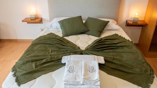 a bed with green blanket and two towels on it at The Village House by CDV in Carrazeda de Anciães