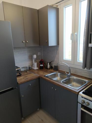 a kitchen with gray cabinets and a sink at Πλατανακι 1 Family Friendly in Andros