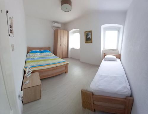 a bedroom with two beds and a table and two windows at Apartments Dabovic in Kotor