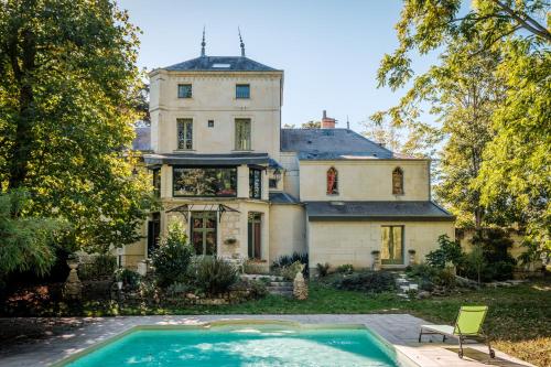 una casa antigua con piscina frente a ella en Clos du Bois Brard B&B, en Saumur