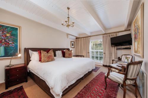 a bedroom with a large bed and a tv at Maison Chablis Guest House in Franschhoek