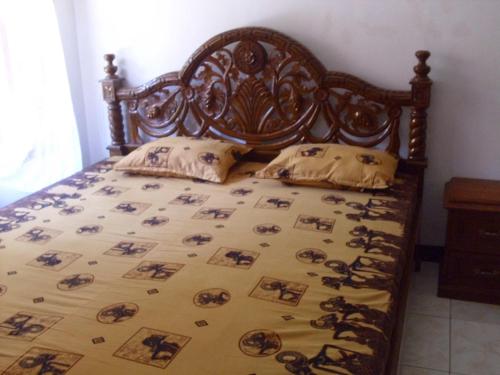 a bed with a wooden headboard and pillows on it at Rinjani Homestay in Pangandaran