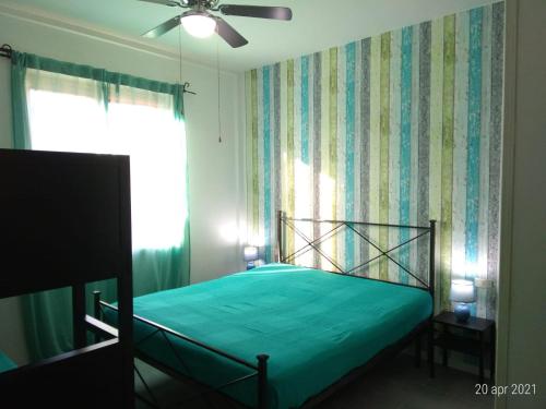 een slaapkamer met een groen bed en een raam bij Casa di Pietro in Porto Azzurro
