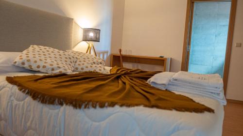 a bed with a brown blanket and pillows on it at The Village House by CDV in Carrazeda de Anciães