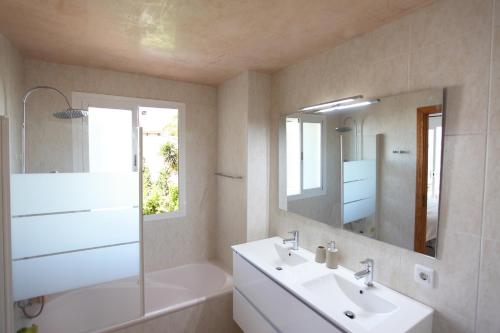 a bathroom with a sink and a tub and a mirror at Villa Beach Alcudia, lovely house with jacuzzi in Alcudia
