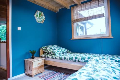 a bedroom with blue walls and a bed and a window at RESETówka nr 2 - domek rodzinny na odludziu in Jaszczurowa