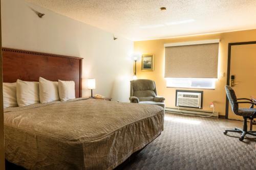 a hotel room with a bed and a chair at Governors Inn a Travelodge by Wyndham in Pierre