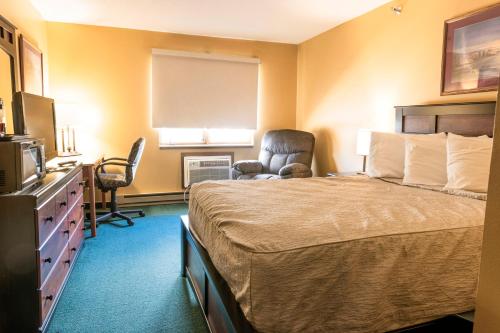 a hotel room with a bed and two chairs at Governors Inn a Travelodge by Wyndham in Pierre