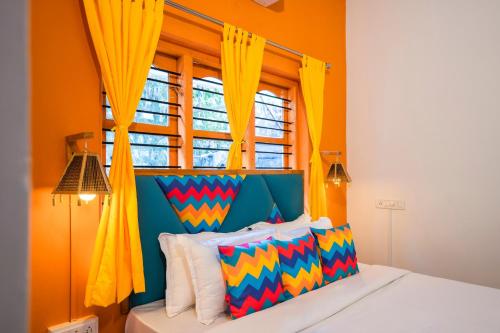 a bedroom with a bed with yellow curtains and a window at goSTOPS Coorg in Madikeri