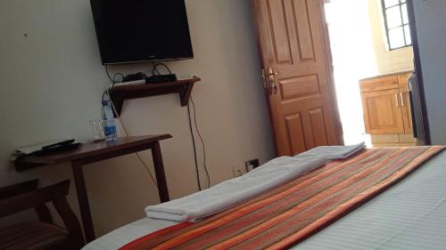 a bedroom with a bed and a television on the wall at dreamplace Gigiri in Nairobi