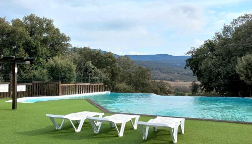 - une piscine avec 2 chaises blanches à côté dans l'établissement Camping Ibie, à Lagorce