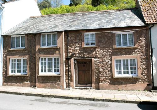 an old stone house with a door and windows at The Oval in Dunster