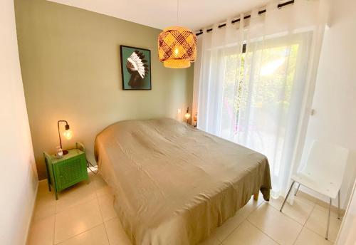 Un dormitorio con una cama y una ventana con una lámpara de araña. en RUBY 2 chambres Terrasse Piscine en Boulouris-sur-Mer