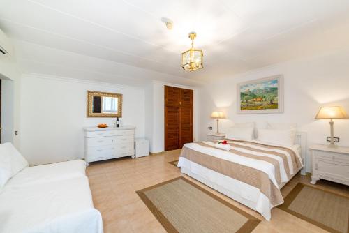 a white bedroom with a bed and a couch at Finca Hotel Rural Predio Son Serra in Can Picafort