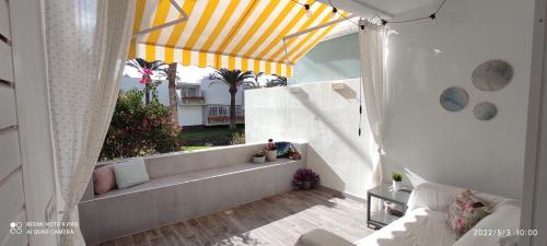 balcón con sofá y dosel amarillo y blanco en Ideal holiday apartment in the south of Tenerife, en Costa del Silencio