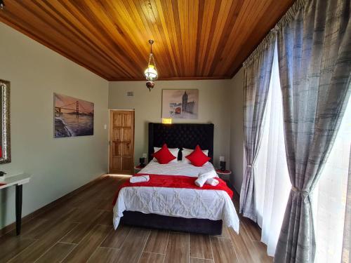 a bedroom with a large bed with red pillows at Danrit Guesthouse - Uncapped wifi in Roodepoort