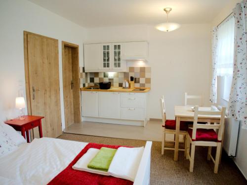 a bedroom with a bed and a table and a kitchen at Apartmány Lhota in Bechyně