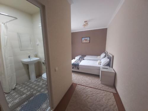 a bedroom with a bed and a bathroom with a sink at Hotel Han in Samarkand