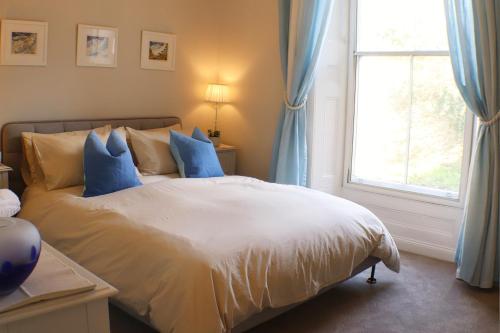 a bedroom with a bed with blue curtains and a window at Seaside Apartment in Aberystwyth