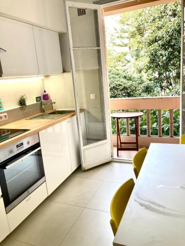 une cuisine avec des armoires blanches, une table et une fenêtre dans l'établissement Edouard VII, à Menton