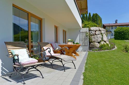 a patio with three chairs and a table on a lawn at Ferienwohnung am Lindenweg in Brixen im Thale