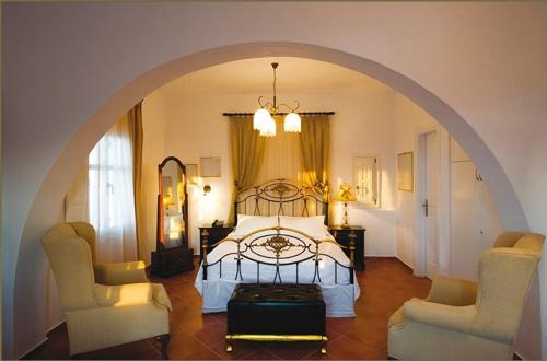 a bedroom with a bed and two chairs at Pegados Villas in Chora Folegandros