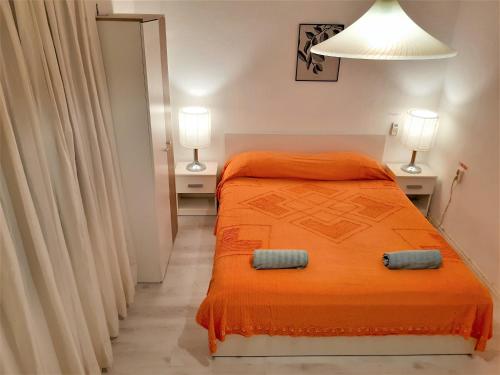 a bedroom with an orange bed and two lamps at Dragan's Den Hostel in Korčula