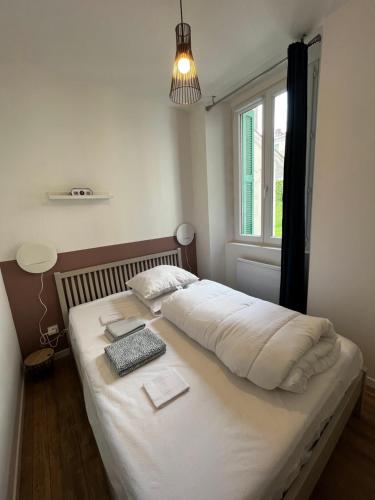 une chambre avec un grand lit blanc avec une fenêtre dans l'établissement Charmant T1 Bis proche Gare et Centre Ville, à Lourdes