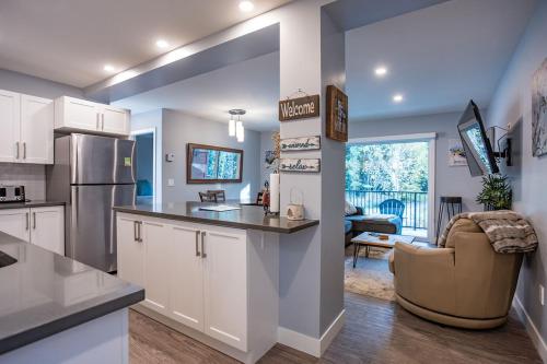 a kitchen with white cabinets and a living room at Al's Escape by Revelstoke Vacations in Revelstoke