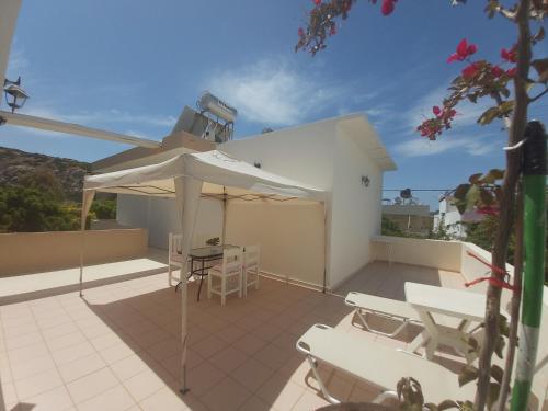 a patio with a table and a white umbrella at Antonios 1 in Matala