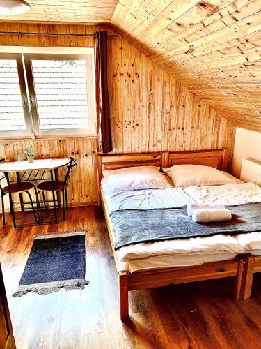a bedroom with a bed in a room with a table at Fakanalas Fogadó in Pásztó