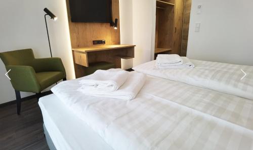 ein Hotelzimmer mit zwei Betten und einem Stuhl in der Unterkunft Waldschlößl in Bruckmühl