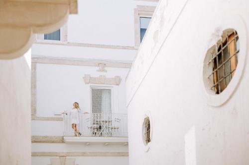 a woman sitting on the balcony of a white building at Dimora Anderì in Polignano a Mare